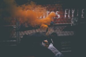 man in black jacket standing near fire. F1-yleisö