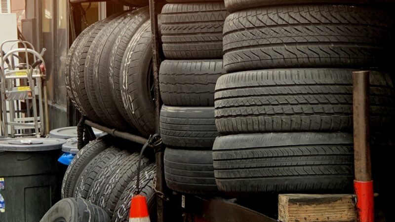 orange traffic cone near pile of vehicle tires